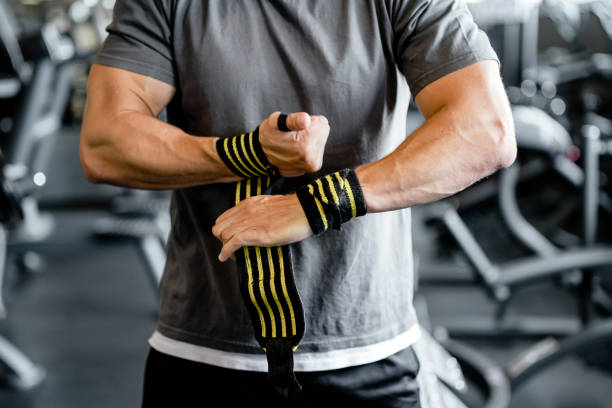 close up of fit muscular man putting on straps in gym
